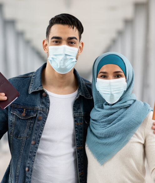 Muslim couple wearing face masks holding passports ready for UAE tourist visa travel